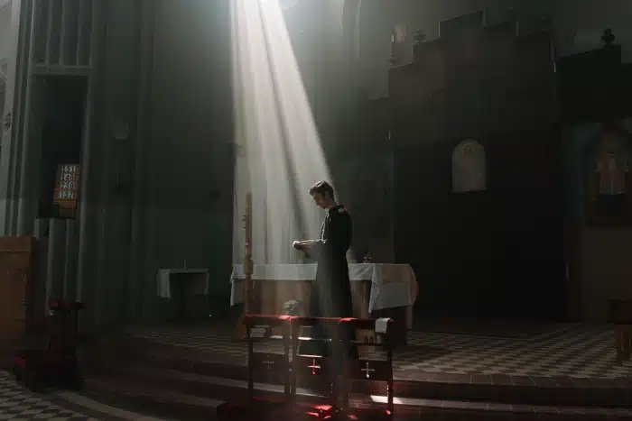 Priest preparing for the Sacrament of Reconciliation through prayer and an examination of conscience in a Catholic church